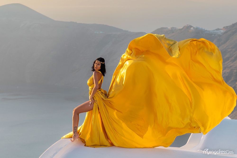 Santorini sunset photoshoot with a yellow gold flying dress