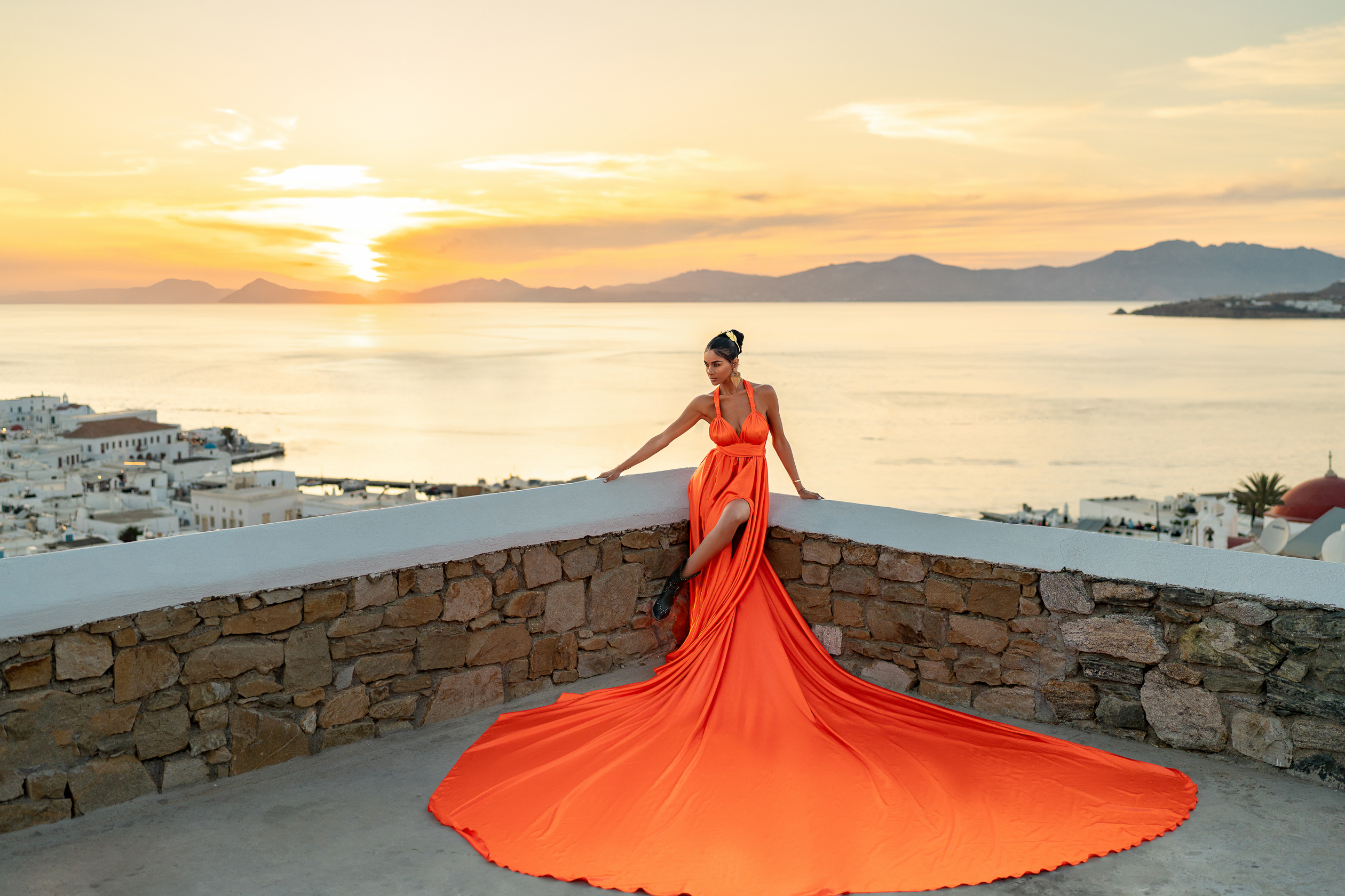 A breathtaking sunset moment in Mykonos — elegance in motion, captured with a vibrant flying dress overlooking the Aegean Sea.