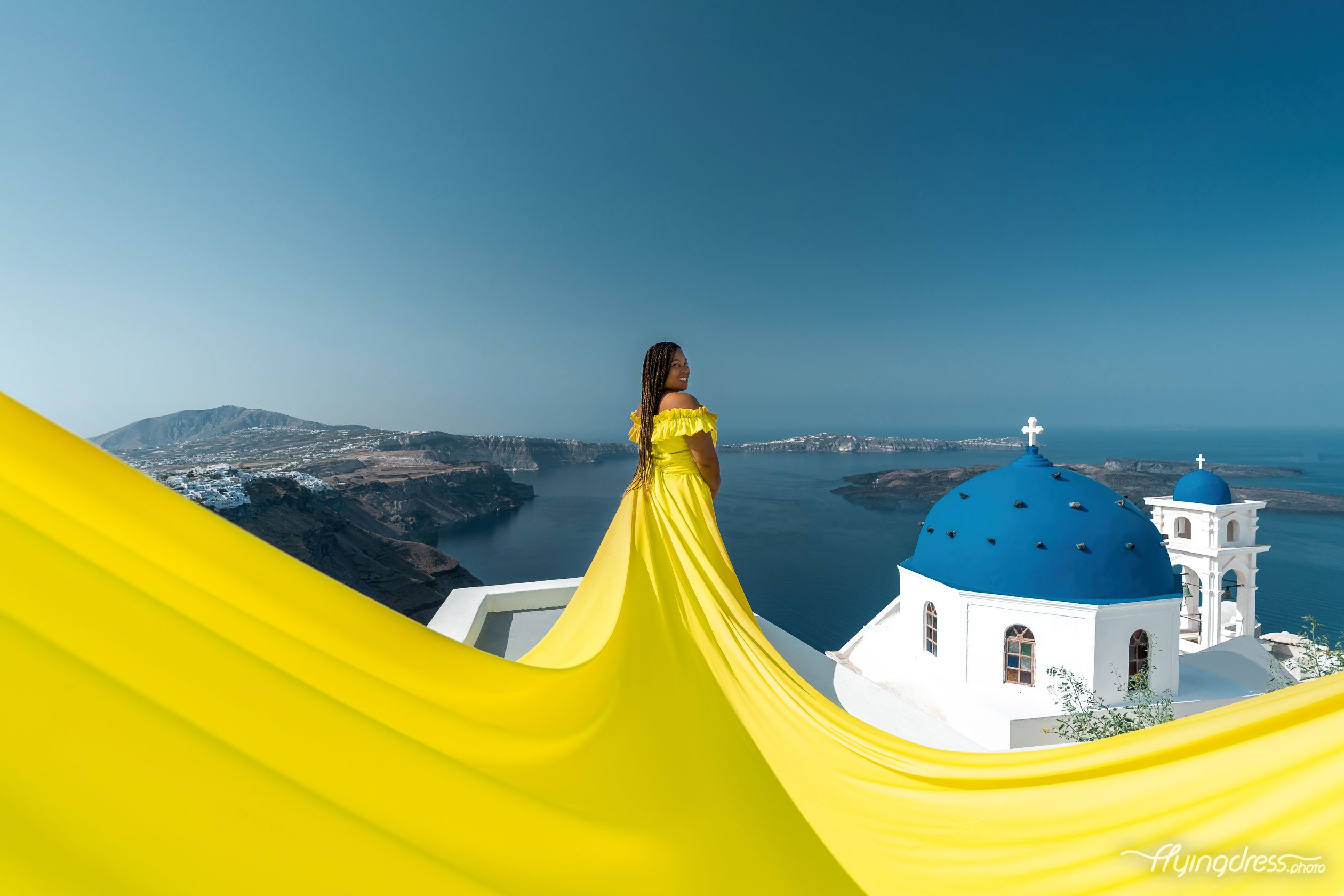Photoshoot by the blue domes in Imerovigli with a neon yellow flying dress
