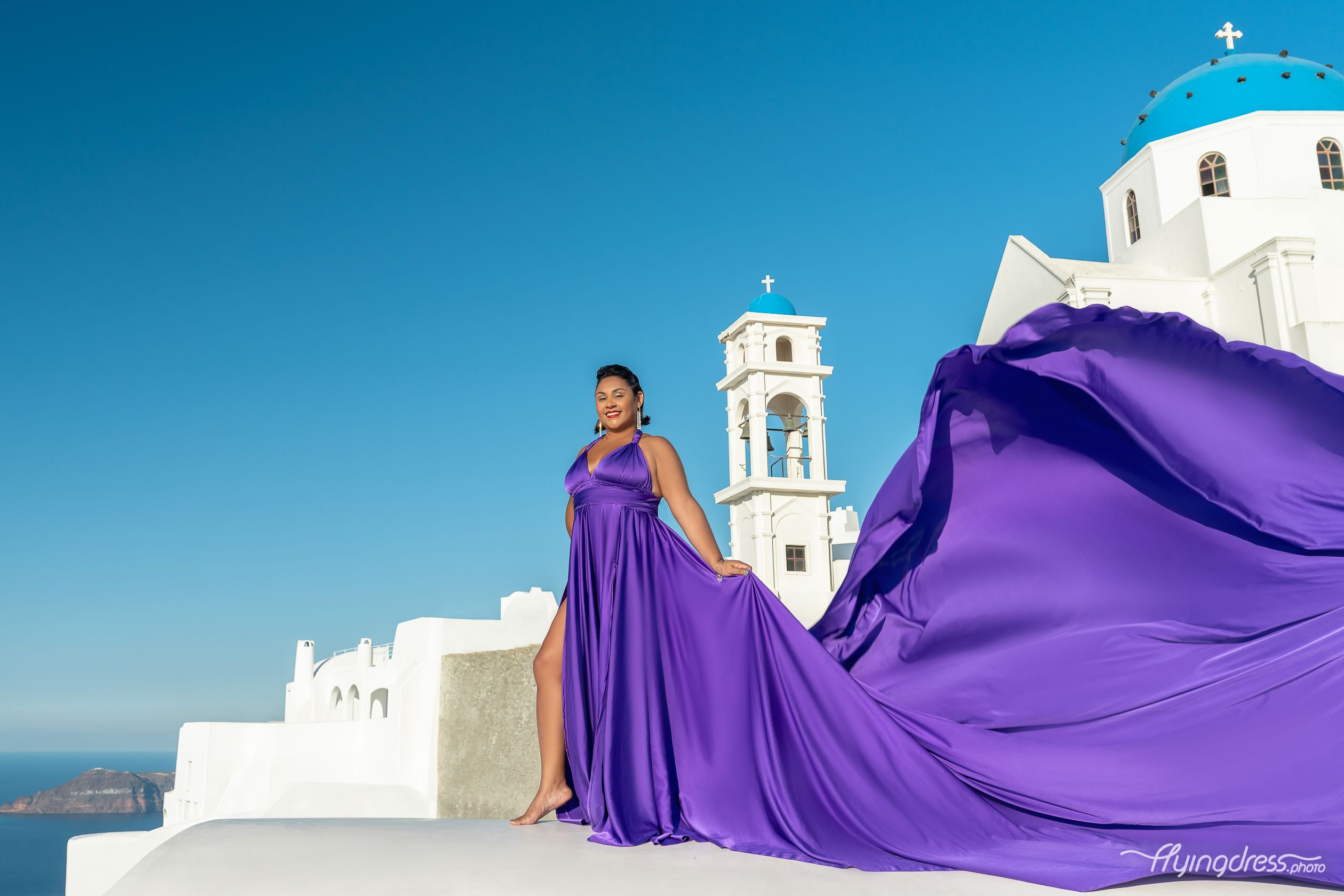 Ultraviolet flying dress photoshoot with blue domes in Santorini