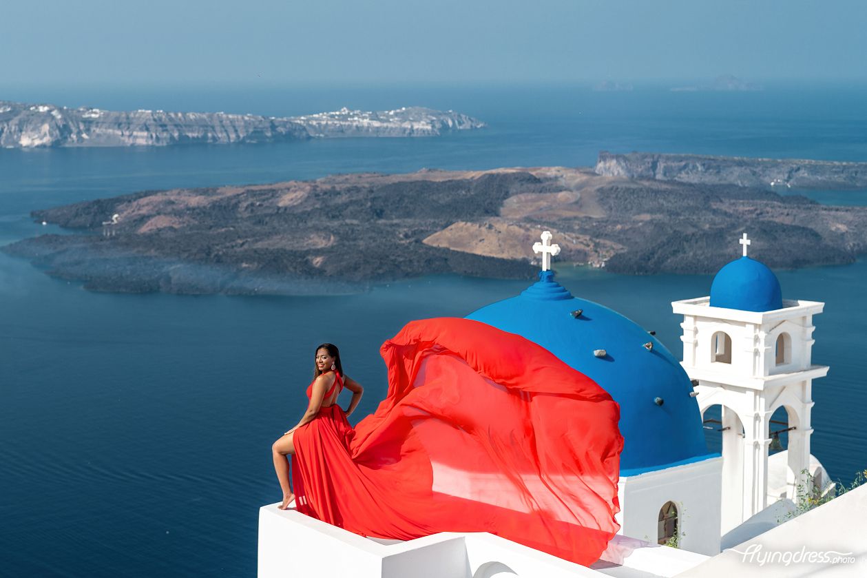 Photoshoot in Imerovigli village by the blue domes with a red flying dress