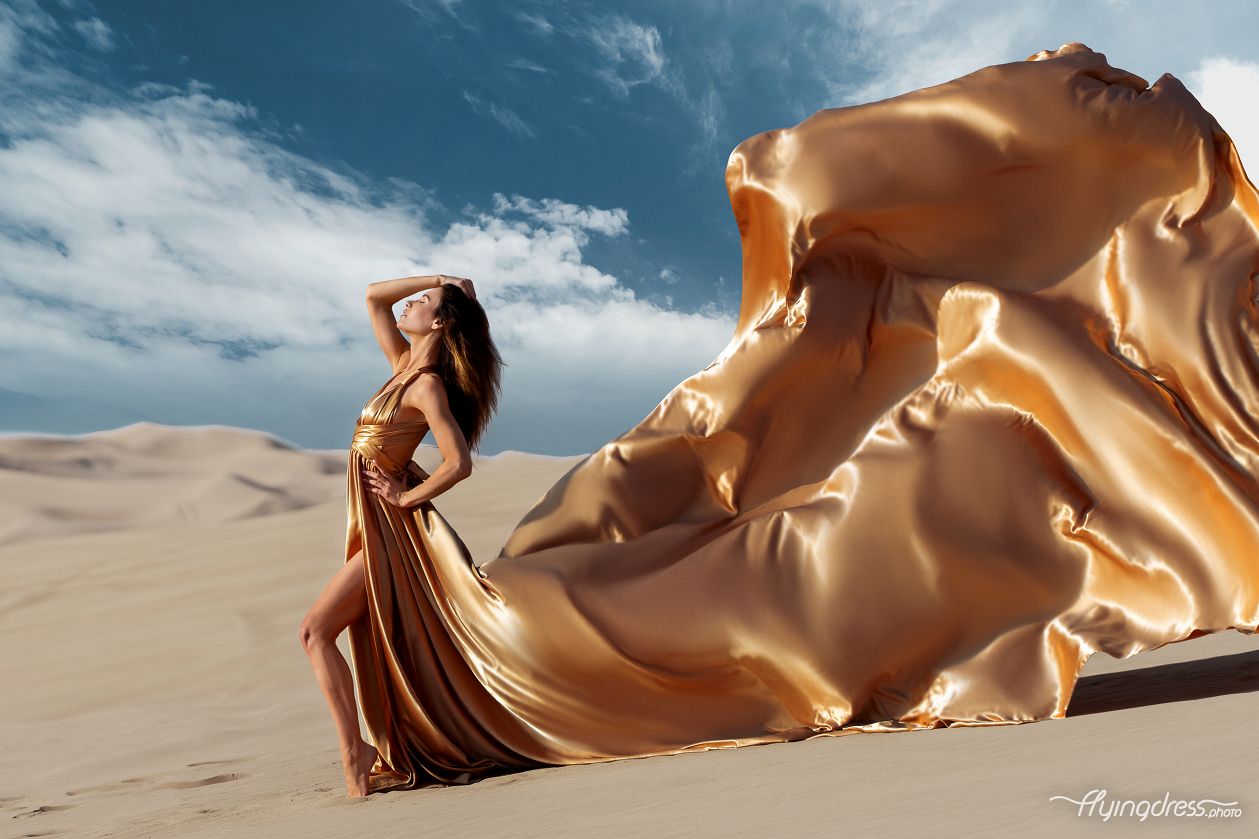 Experience glamour in the Dubai red sand desert with our model donning a stunning gold flying dress. This photoshoot combines luxury and nature for a captivating visual feast.