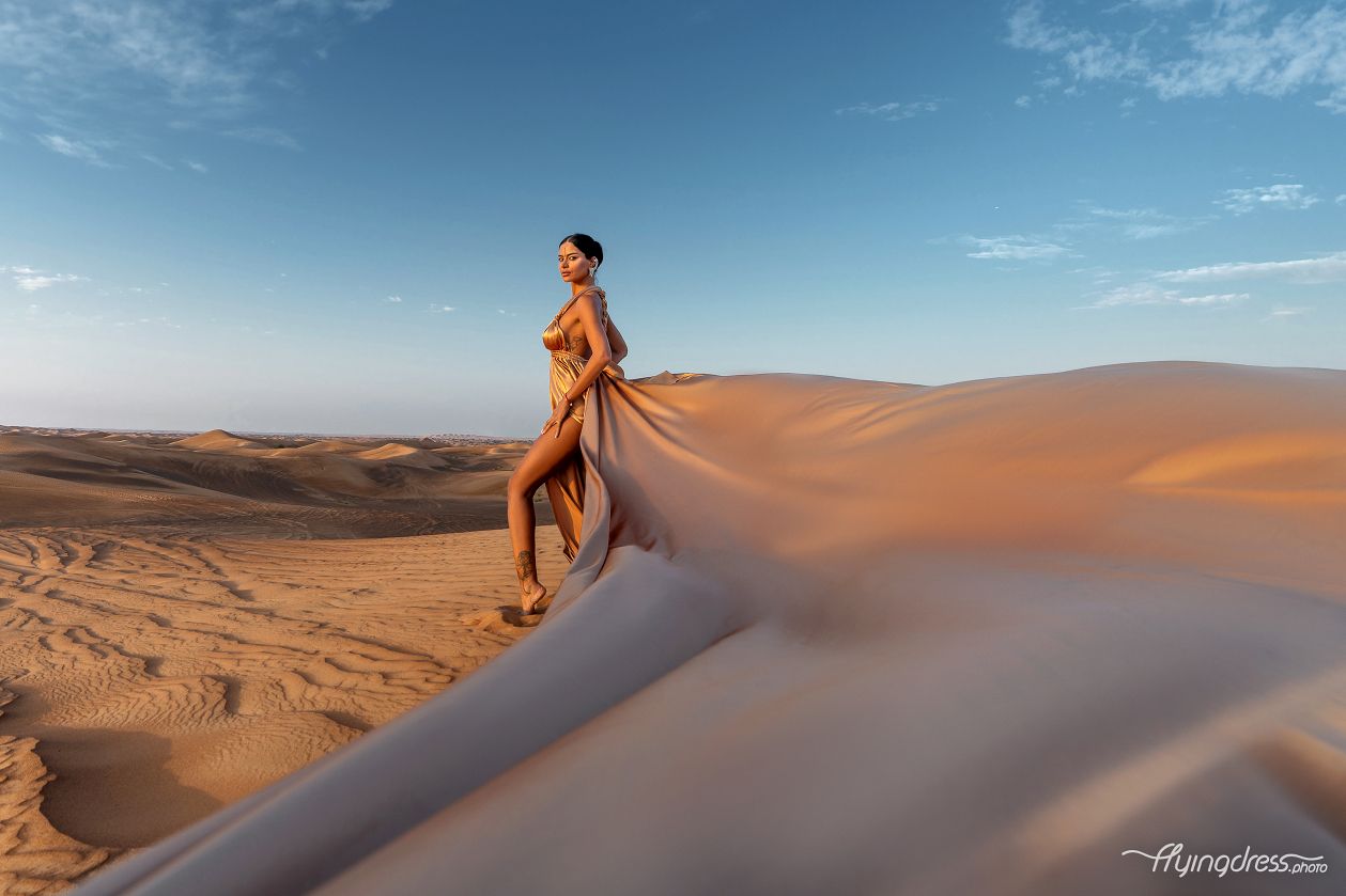 Embrace the golden allure of the desert as our model dons a stunning gold dress.