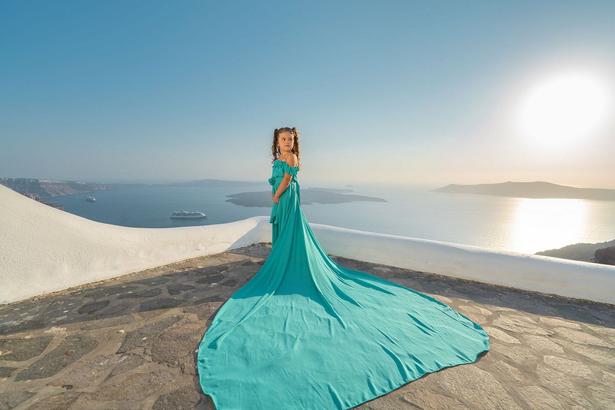 Little girl with a tiffany blue flying dress in Santorini
