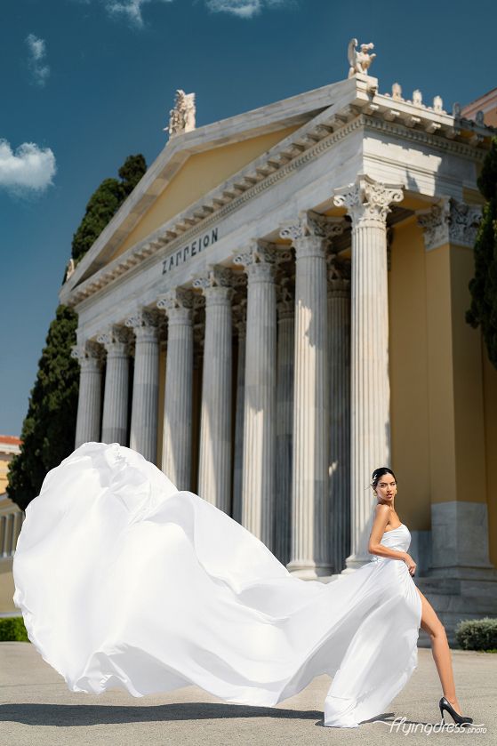 Gracefully moving amidst the backdrop of Zappeion, a girl dons a flowing white dress, her ethereal presence harmonizing with the historic charm of Athens in a captivating scene.