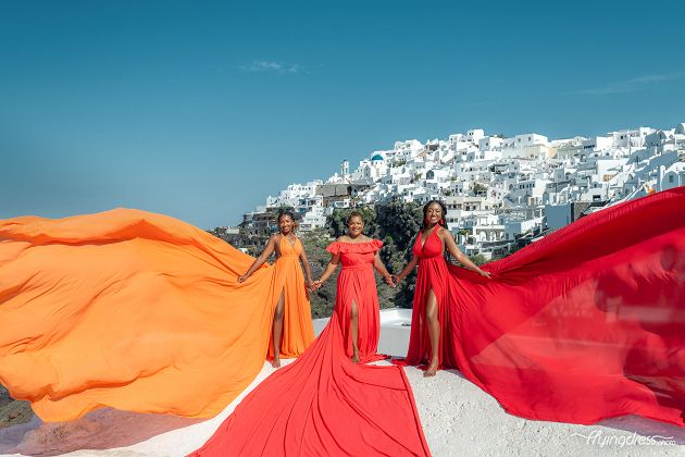 In a heartwarming family photoshoot, a loving mother and her two daughters radiate happiness and love amidst the enchanting beauty of Santorini, their bond captured in a cherished moment that encapsulates the joy and connection they share.