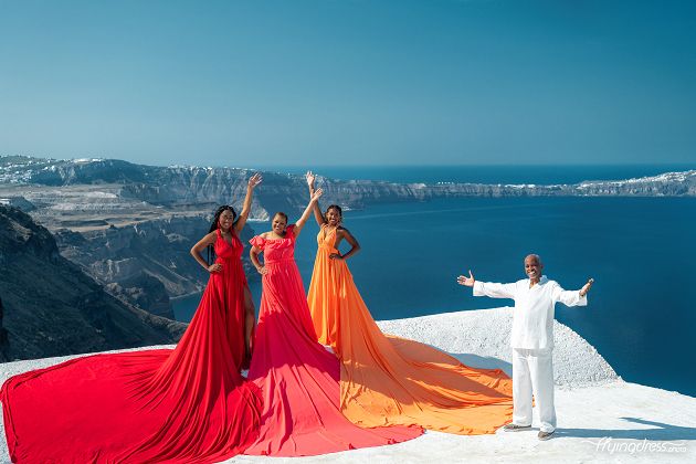 A joyful family embraces the beauty of Santorini in a photoshoot, with three elegant ladies and their loving husband, capturing a moment of togetherness and creating lasting memories against the backdrop of the island's breathtaking landscapes.