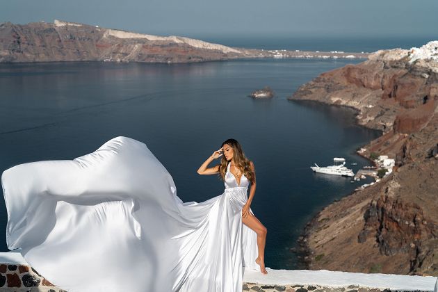 White flying dress photoshoot with Oia village (Santorini) at the background