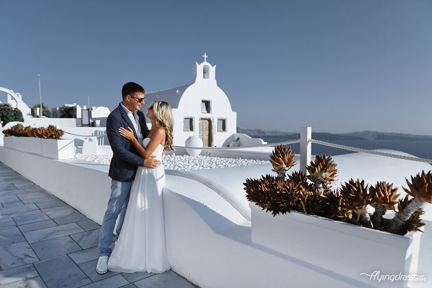 A couple indulges in a photoshoot amidst the enchanting village of Oia in Santorini, their love becoming an integral part of the picturesque streets, creating an enduring image of romance and bliss.