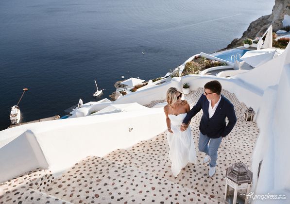 Hand in hand, a couple gracefully ascends the iconic stairs of Santorini, their steps filled with anticipation and joy, symbolizing their shared journey of love and the promise of a beautiful future together.