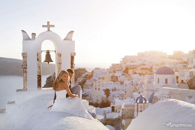 A couple shares a quiet moment, seated together in Santorini, their eyes locked in a gaze that speaks volumes of their deep connection and the serenity found in the embrace of this enchanting destination.