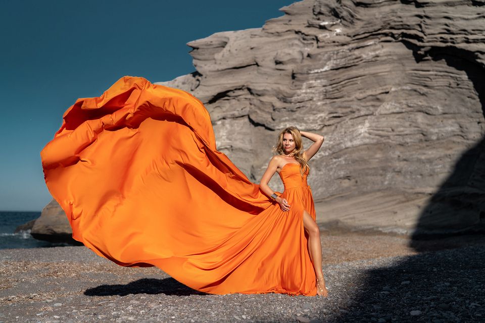 Orange flying dress shoot at the black beach of Columbus, Santorini
