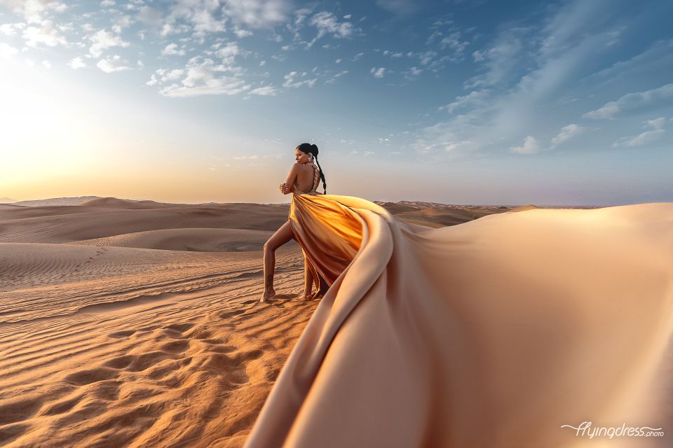 Model shines in a flying dress photoshoot amidst Dubai's desert beauty, a striking blend of elegance against the backdrop of golden sands.