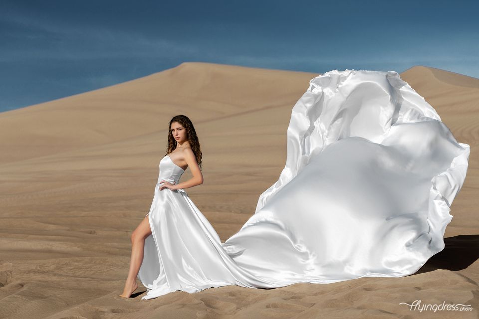 Captivate in the desert's beauty with our model donning a flowing white dress. This photoshoot elevates elegance against golden sands, a stunning blend of grace and nature.