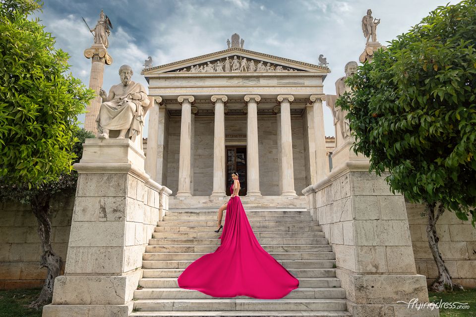 Amidst the iconic setting of the National University of Athens, a model enchants in a vibrant fuchsia flowing dress, infusing the scene with a burst of color and elegance in a captivating photoshoot