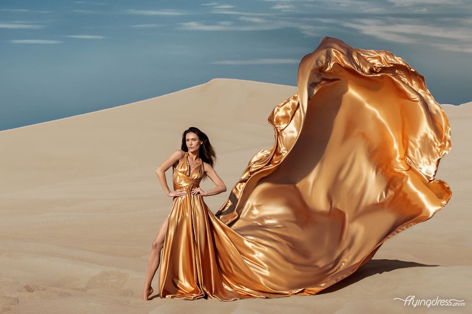 In the golden embrace of Dubai's desert, a vision unfolds as a girl gracefully soars in a flying dress, capturing the essence of elegance against the breathtaking backdrop of endless dunes.