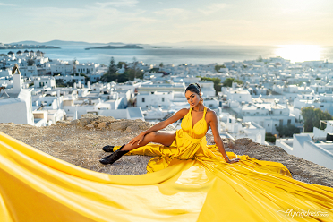 Revel in the radiant beauty of Mykonos with a flying dress photoshoot, where the vibrant yellow gown shines against the backdrop of white-washed buildings and the shimmering Aegean Sea.