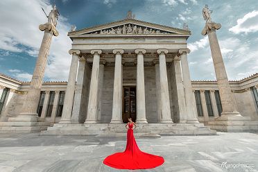 At the National University of Athens, a model commands attention in a flowing red dress, epitomizing elegance and grace against the backdrop of academia and history in a striking photoshoot