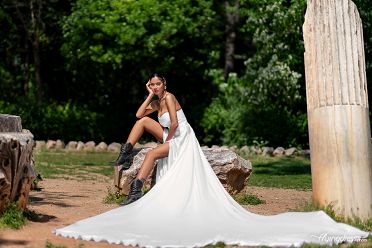 In the serene setting of the National Garden, a model reclines gracefully in a white long dress, epitomizing tranquility and elegance in a captivating photoshoot.