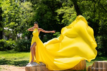 Amidst the verdant tranquility of Athens National Garden, a model enchants in a luminous yellow flying dress, casting a radiant glow against the serene backdrop in a captivating photoshoot