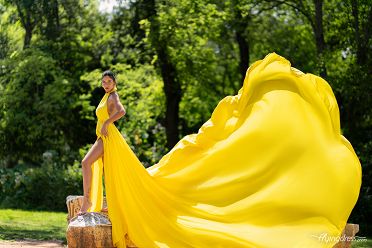 In the serene ambiance of the Garden of Athens, a model dazzles in a flowing yellow dress, her radiant presence adding a touch of sunshine to the tranquil surroundings in a captivating photoshoot.